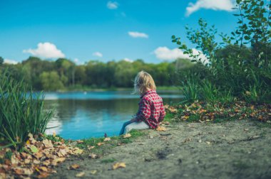 Küçük bir yürümeye başlayan bir orman gölette başına oturmuş