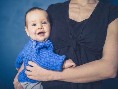 Genç bir anne onu mutlu gülümseyen bebek tutan