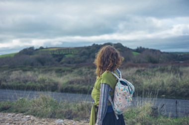 Genç bir anne ile bebeği bir askı içinde kırsal kesimde yürüyor