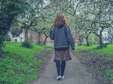 Genç bir kadın parkta baharda yürüyor