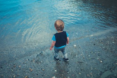 Küçük şirin bir yürümeye başlayan çocuk su ile oynuyor