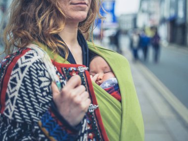 Sokakta genç bir anne ile bebeği bir taşıyıcı askı