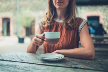 Genç bir kadın dışarıda kahve içiyor