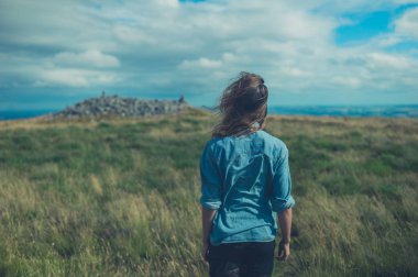 Genç bir kadın bir alanda rüzgarlı bir günde duruyor