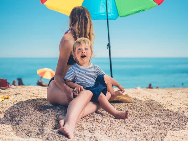 Egy Fiatal Anya Kisgyermek Pihentető Alatt Egy Napernyő Strandon — Stock Fotó