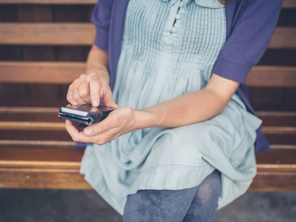 Genç Bir Kadın Dışında Bir Bankta Oturan Bir Akıllı Telefon — Stok fotoğraf