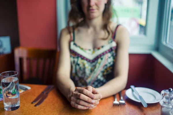 一位年轻女子正坐在餐馆里等着吃午饭 — 图库照片