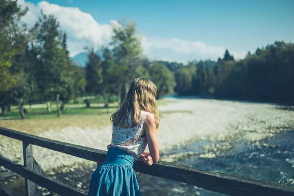 A young woman is standing on a bridge in nature