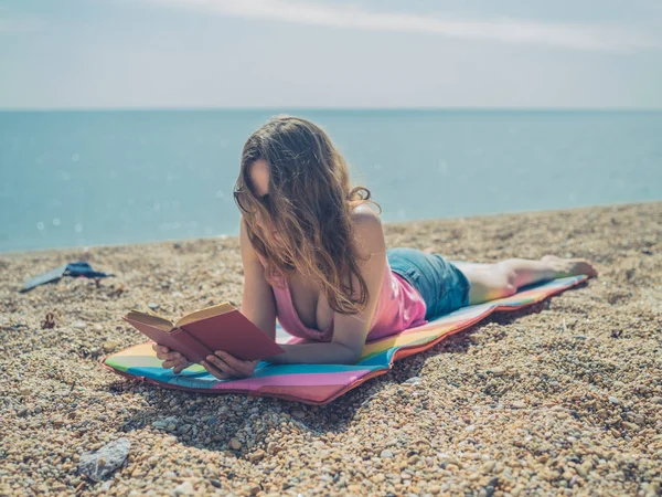 Una Joven Está Tumbada Playa Está Leyendo Libro Día Soleado —  Fotos de Stock