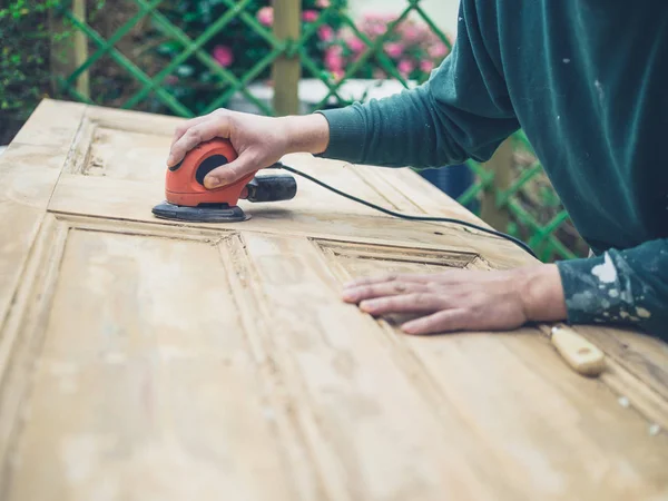 Ung Man Slipning Gammal Dörr Med Elektrisk Slipmaskin — Stockfoto