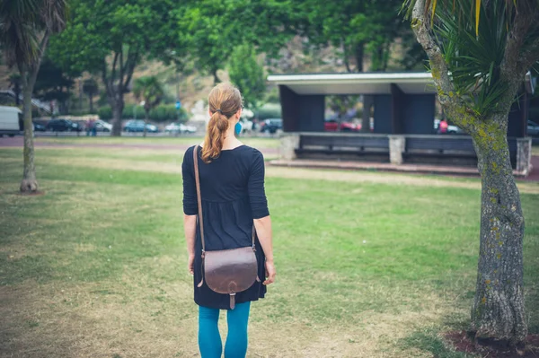 若い女性が公園に立っていると避難所を見ています — ストック写真