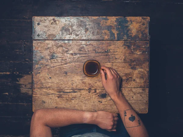 Overhead shot of man drinking coffee at a wooden table