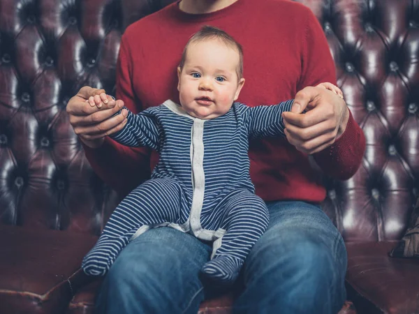 Joven Padre Está Sentado Sofá Con Pequeño Bebé —  Fotos de Stock