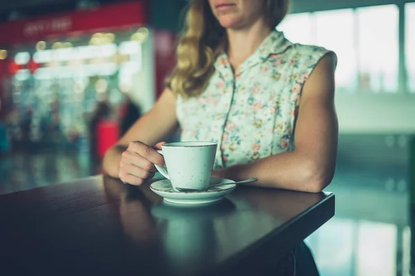若い女性が空港でコーヒーを飲む — ストック写真
