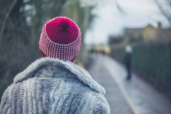 一个穿着冬衣 头戴帽子的年轻女子站在公园外 — 图库照片