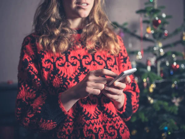 Een Jonge Vrouw Met Behulp Van Haar Smartphone Door Kerstboom — Stockfoto