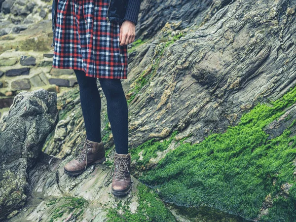 一个年轻女子穿着裙子站在自然界的岩石上的腿 — 图库照片