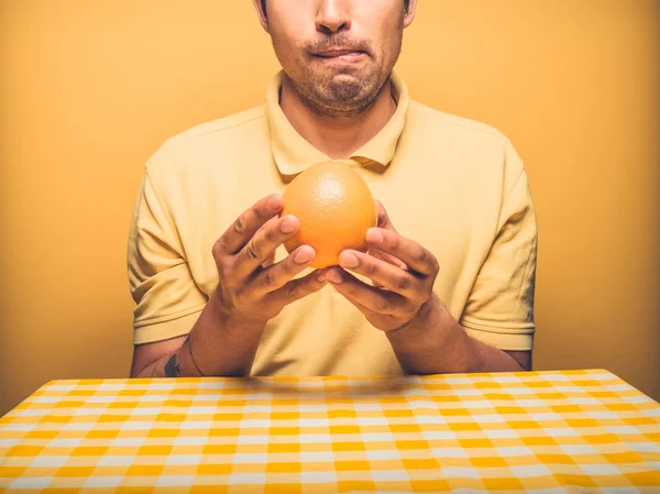テーブルに座っている若い男はグレープ フルーツを食べることの見通しについて興奮しているとほとんど待つことができます — ストック写真