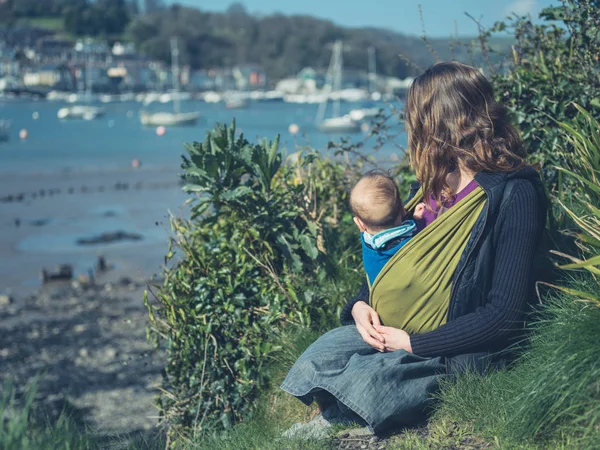 Young Mother Sitting Nature Her Baby Looking Ships River — Stock Photo, Image