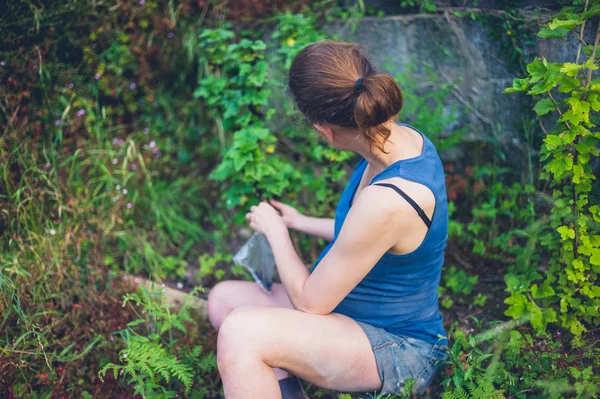 一个年轻的孕妇正坐在她的花园里 坐在一棵黑醋栗旁 — 图库照片