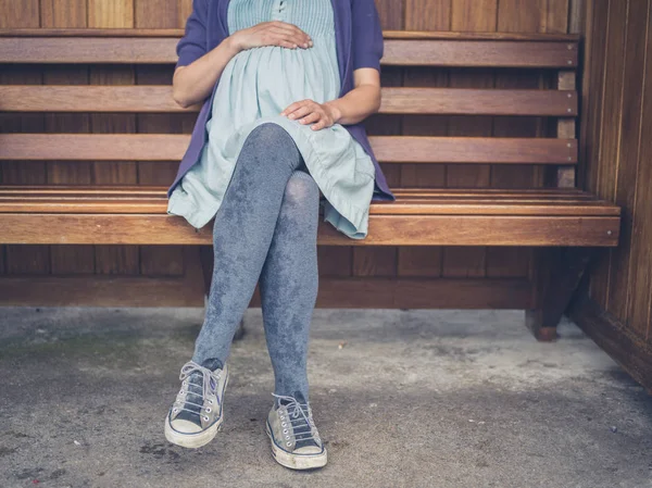 一个年轻的孕妇在避难所的长凳上休息 — 图库照片