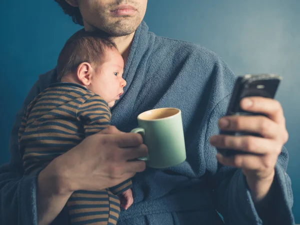 Ung Fader Morgonrock Använder Smartphone Fördriva Tiden Holdingen Mugg Och — Stockfoto