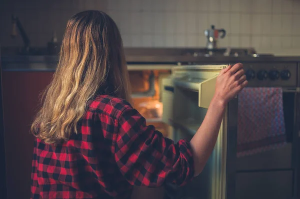 一个年轻的女人正在打开她冰箱的门 — 图库照片
