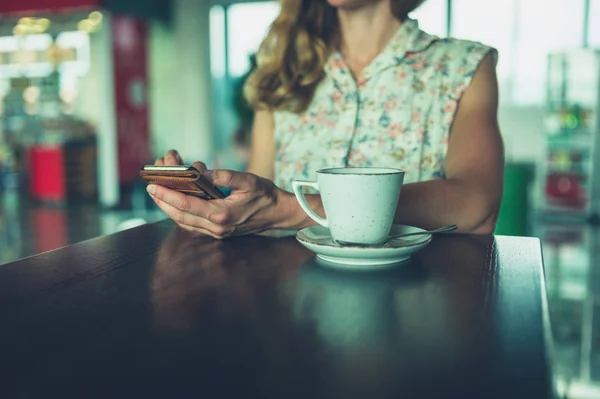여자는 커피를 마시고 공항에서 그녀의 스마트폰 — 스톡 사진