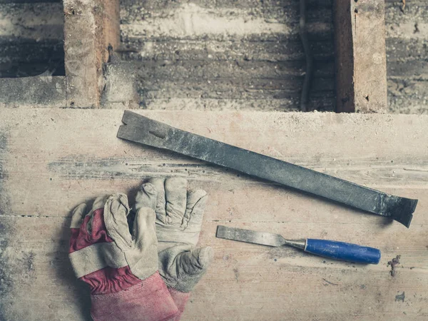 木地板上的一副带撬棍和凿子的建筑工人手套 — 图库照片