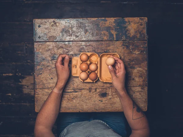 男子拿着鸡蛋坐在桌旁的头顶射门 — 图库照片