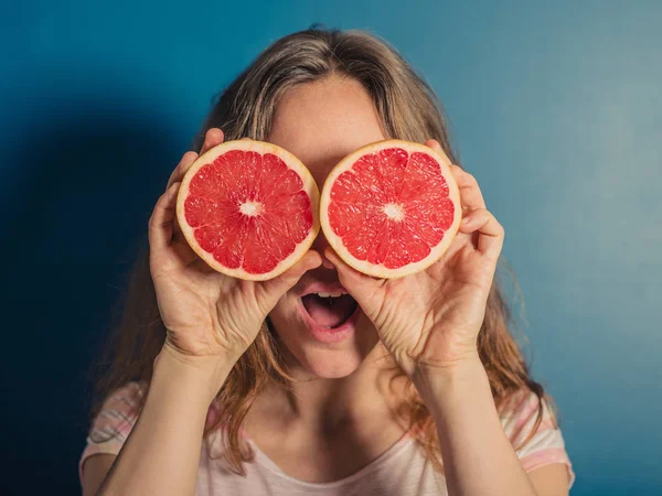 一名年轻女子用两个半的葡萄柚作为双筒望远镜 — 图库照片