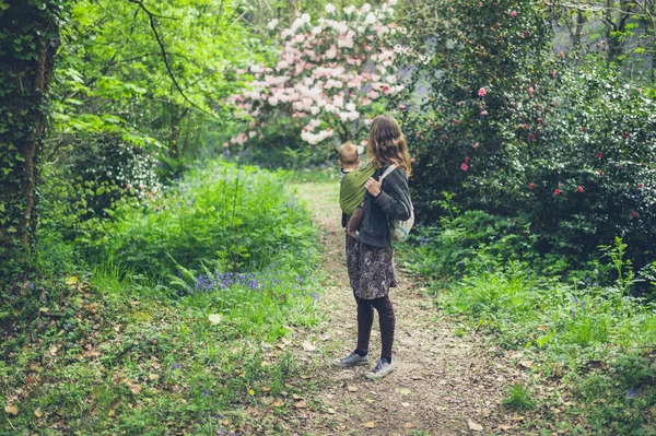 若い母親はスリングで赤ちゃんと庭に立っています — ストック写真