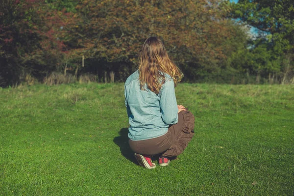 在一个阳光明媚的秋日 一位年轻女子正在草地上放松 — 图库照片