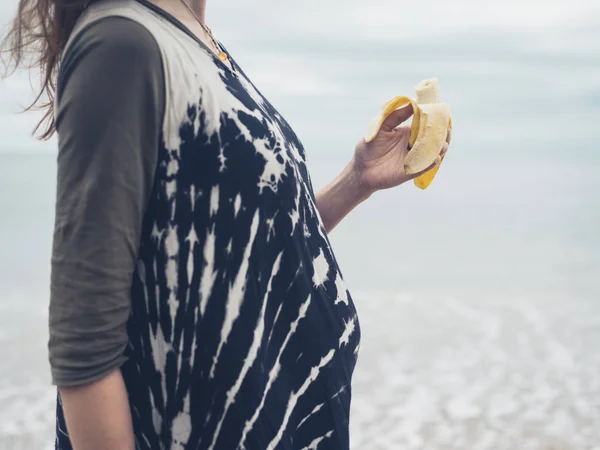 Een Zwangere Vrouw Het Eten Van Een Banaan Het Strand — Stockfoto