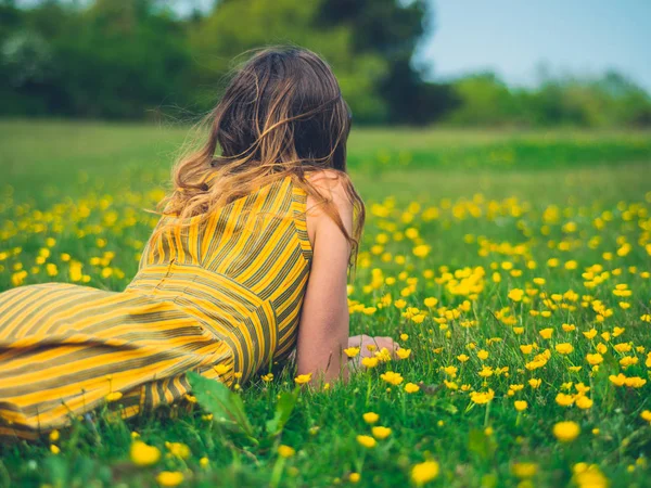 年轻女子的后景色躺在草地上 周围环绕着蝴蝶 — 图库照片