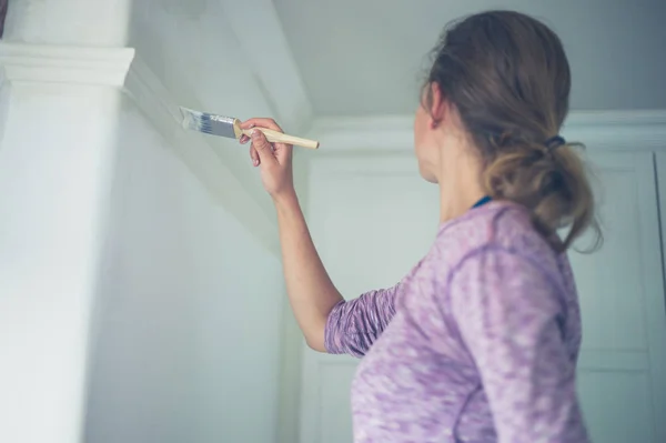 一个年轻的女人正在粉刷天花板 — 图库照片