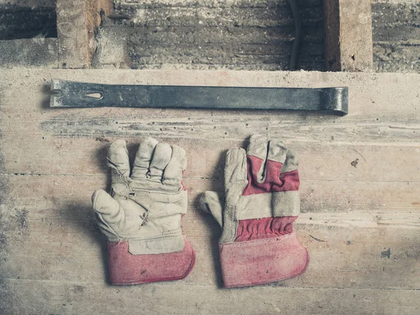 Ein Paar Arbeitshandschuhe Und Ein Brecheisen Auf Einem Holzboden — Stockfoto