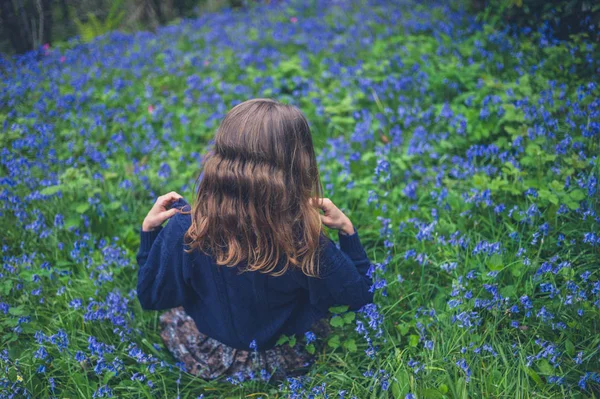 若い女性はブルーベルの草原に座っています — ストック写真