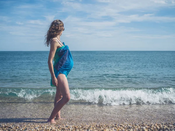 一名身穿沙龙服装的年轻孕妇站在海滩上 — 图库照片