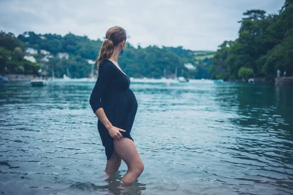 一位年轻的孕妇站在湖里 正在享受沉默 — 图库照片