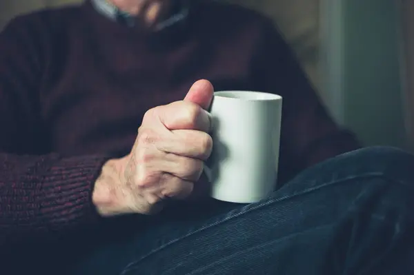 年配の男性は 自宅で紅茶をマグでリラックス — ストック写真