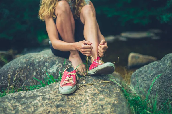 Genç Bir Kadın Ayakkabıları Bir Nehir Tarafından Bağlıyor — Stok fotoğraf
