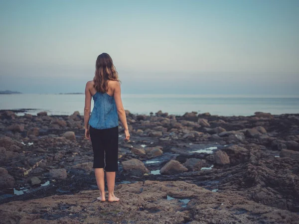日落时 年轻女子的后景站在海岸上 — 图库照片