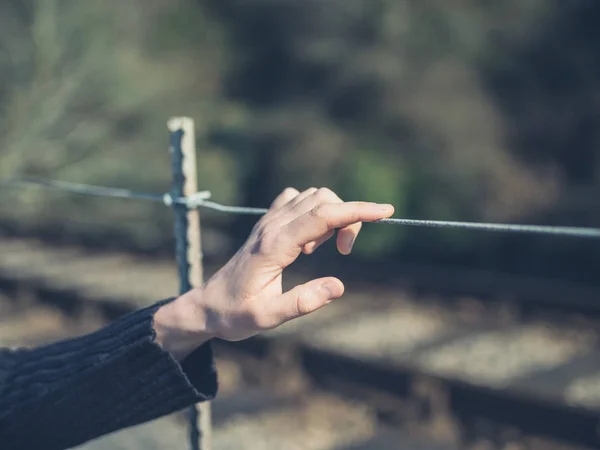 若い女性の手に触れているワイヤー フェンス屋外 — ストック写真