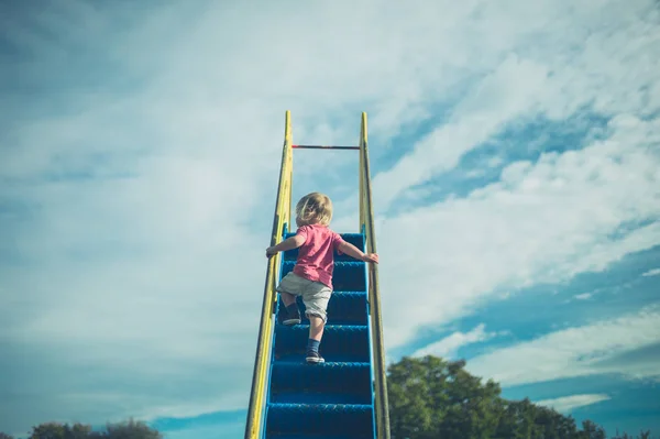 小さな幼児がスライドを登っています — ストック写真