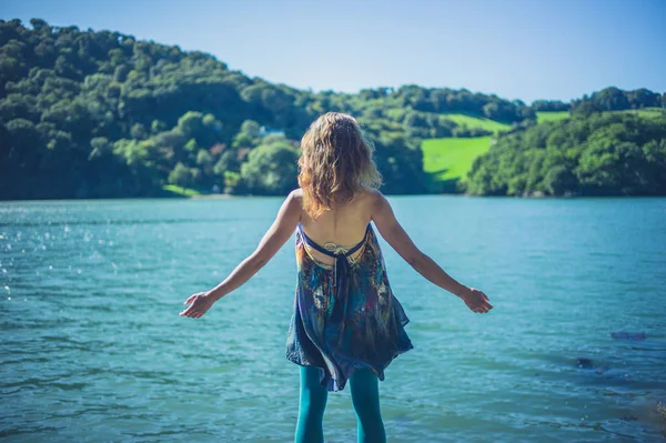 一位年轻女子在水中欢呼雀跃地举起双臂 — 图库照片