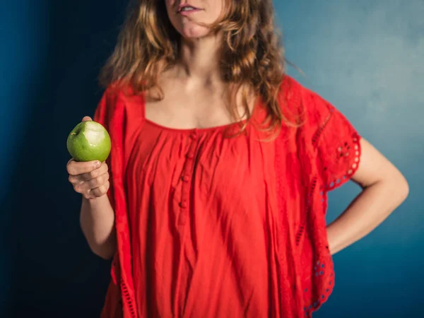 一个穿红色衣服的年轻女子拿着一个吃了一半的苹果 — 图库照片