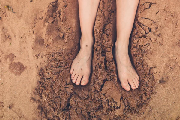 The feet of a young woman relaxing in the sand