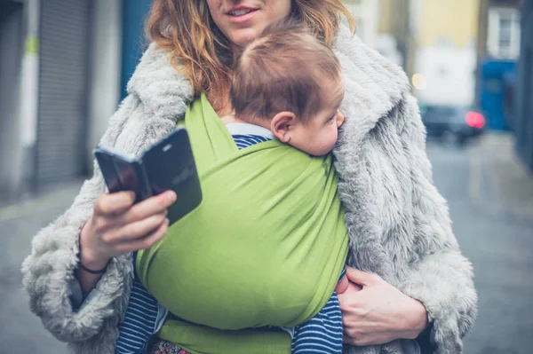 Genç Bir Anne Bebeğini Bir Taşıyıcı Askı Ile Şehirde Onun — Stok fotoğraf