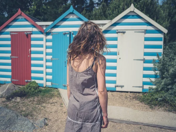 Young Woman Wind Swept Hair Standing Some Beach Huts — Stock Photo, Image